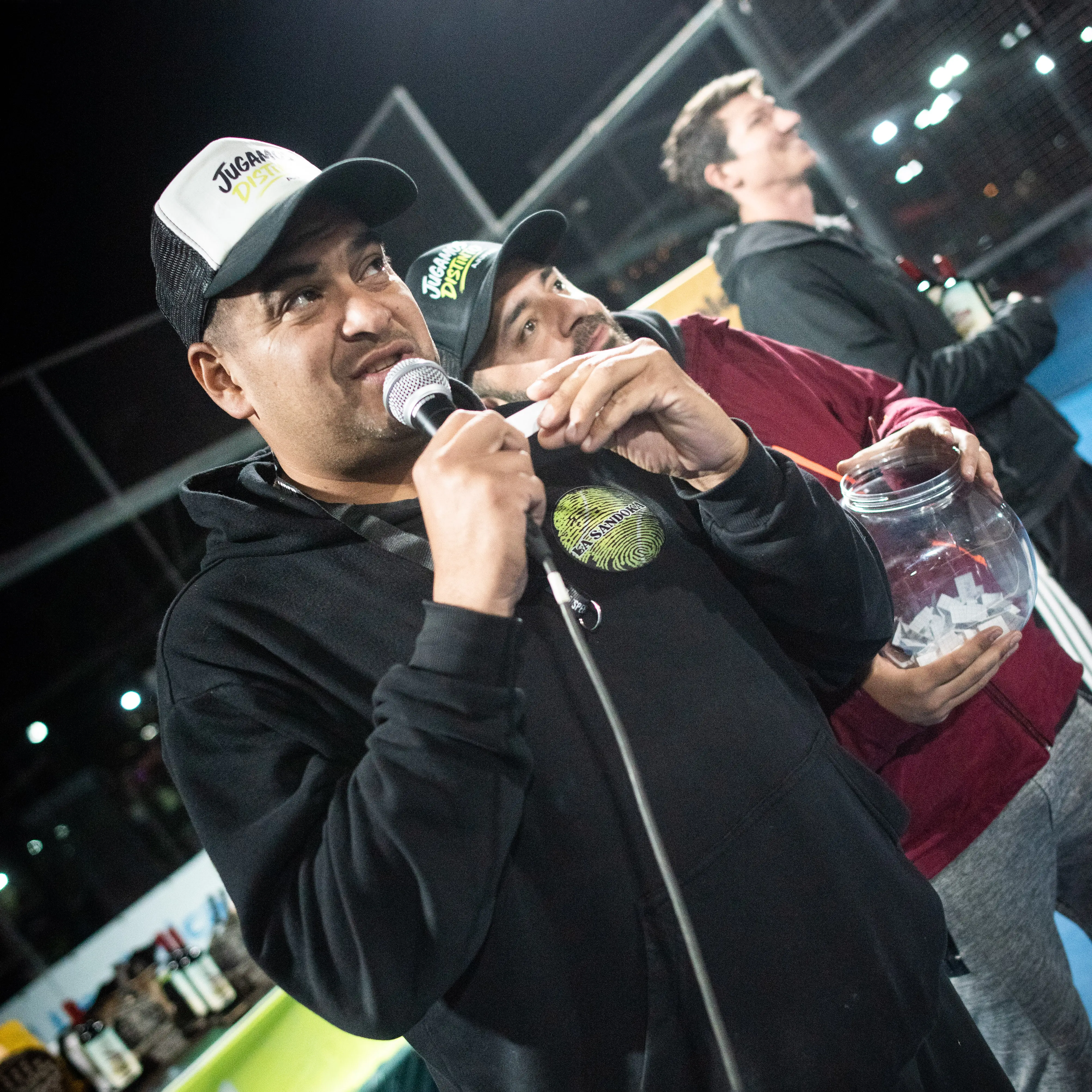 Presentador realizando sorteos de premios durante las finales de la liga AJuPaM con sponsors visibles